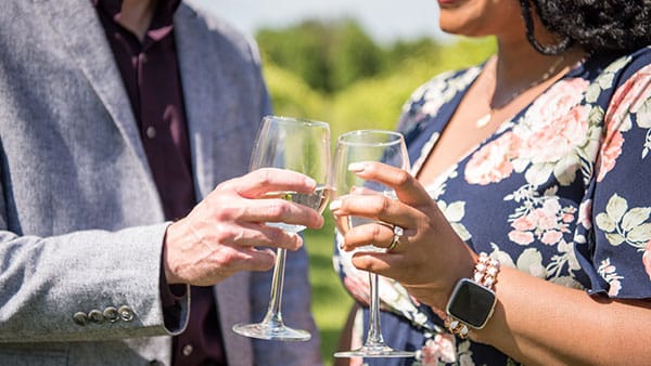 Close-up of couple toasting white wine glasses during a romantic moment at Gervasi Vineyard