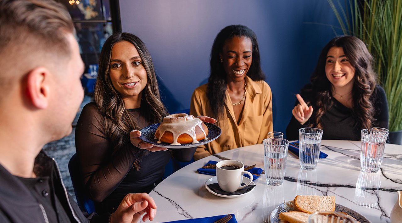 A glazed pastry is served at a marble table as friends gather for brunch inside OLINDA at Gervasi in Jackson Township