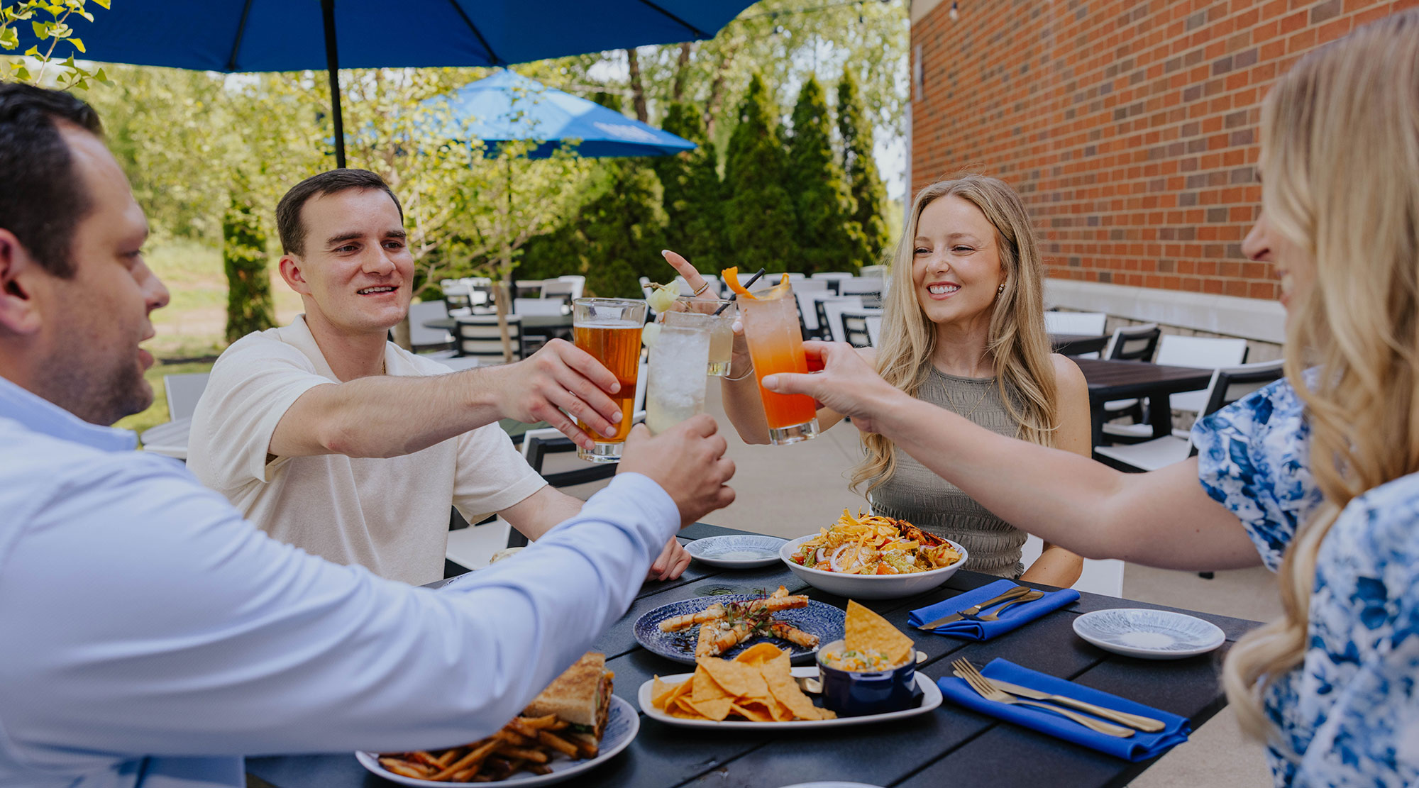 Outdoor dining at OLINDA in Jackson Township with guests toasting cocktails over appetizers on the Gervasi restaurant patio